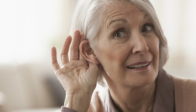 senior caucasian woman cupping her ear to listen